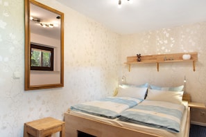 Une chambre à coucher comprenant un lit, une table de chevet, une commode, un miroir et une étagère murale agrémentée d’objets décoratifs.
