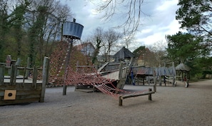 A playground with a rope bridge, wooden structures, and a water tower. - Apartment Near the Beach with Private Terrace and Wi-Fi (Heringsdorf)