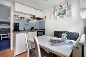 Une cuisine de taille réduite avec des meubles blancs, une table à manger et un canapé.