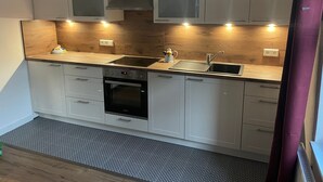 Uma cozinha moderna com armários brancos, uma pia de aço inoxidável e um forno.