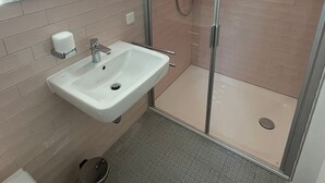 Een moderne badkamer met een wastafel, spiegel en een douchecabine van glas.