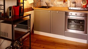 Une cuisine avec des meubles de rangement en bois, une cuisinière et un plan de travail sur lequel sont disposés divers ustensiles de cuisine.