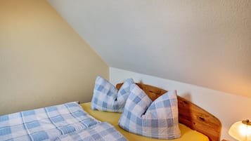 Een slaapkamer met een bed, geruit beddengoed, een houten hoofdbord en een bedlampje.