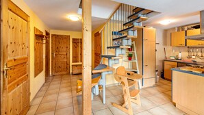 Une cuisine avec des meubles en bois, un coin repas avec des chaises et un escalier.
