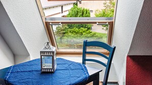 Una habitación con tragaluz, una mesa con mantel azul, una silla y un farol.