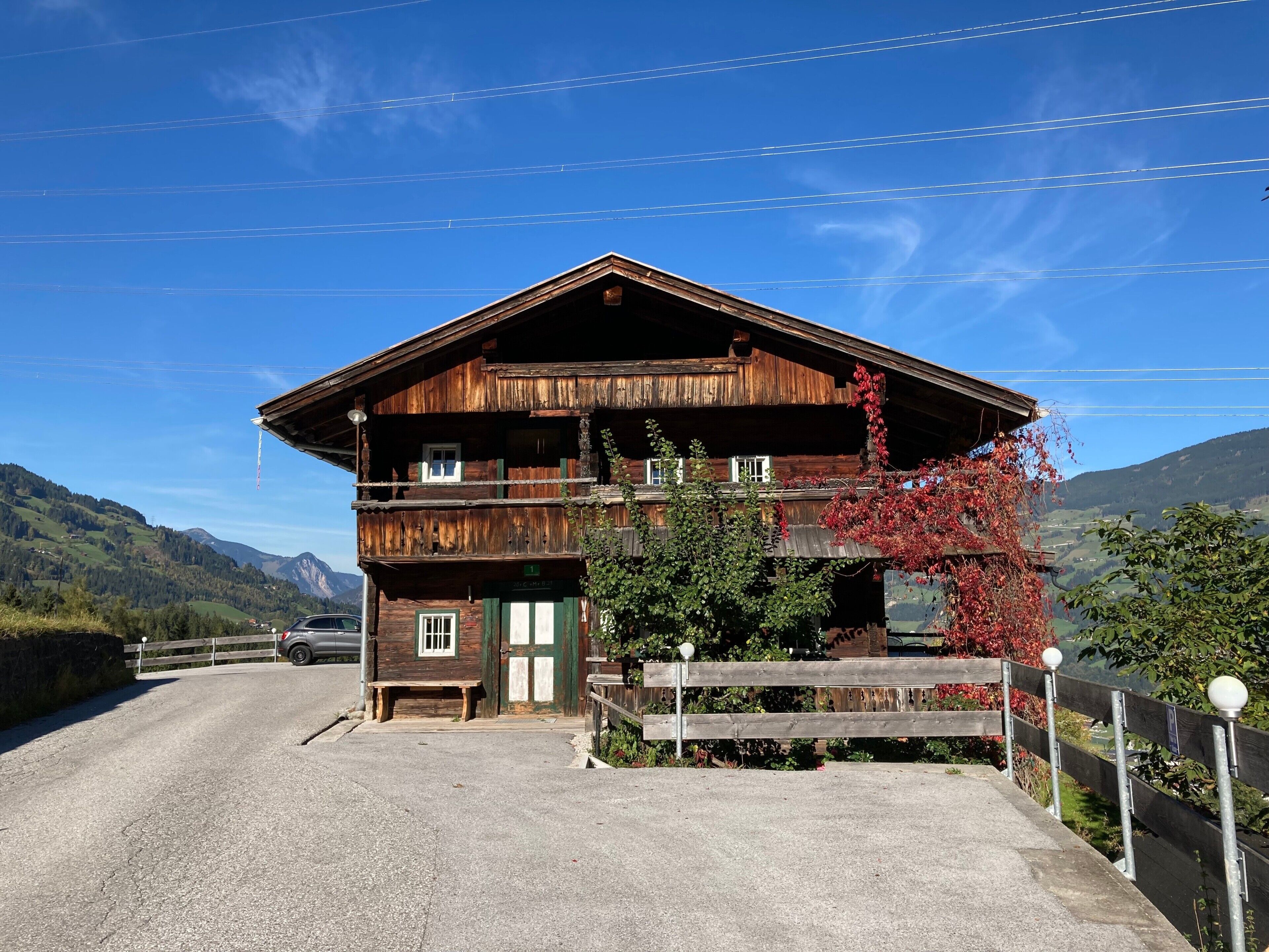 Un chalet en bois doté d’un balcon, d’une allée en gravier et surplombant un paysage montagneux.
