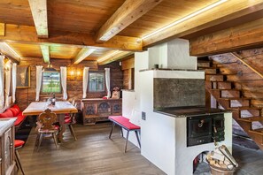 Ein rustikales Blockhaus-Interieur mit Holzbalken, einem Kamin, einem Esstisch und einer Bank.