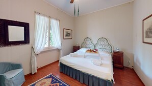 Un dormitorio ordenado con cama, una silla, una mesita de noche y un cuadro en la pared.