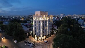Un hôtel à plusieurs étages, doté d’un design moderne, avec une entrée imposante et une façade bien éclairée.