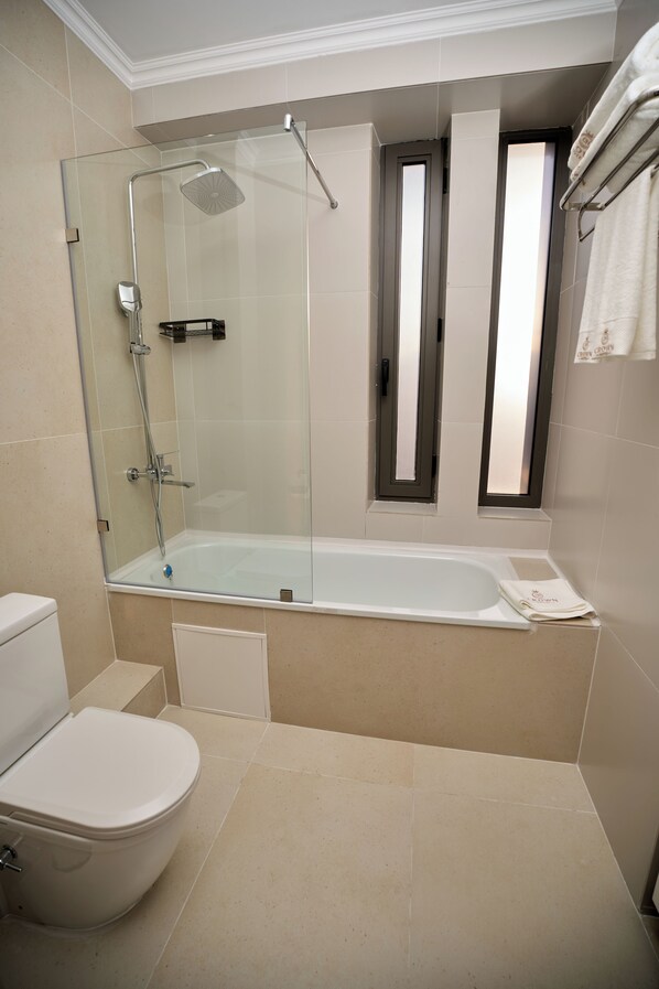 A modern bathroom with a glass-enclosed shower, a bathtub, and a toilet.