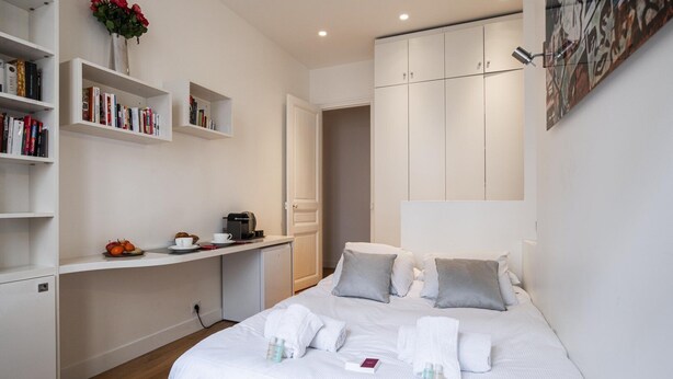 A neatly arranged bedroom with a bed, bedside tables, a desk, and a bookshelf. - Tiny House St Germain /AC (Paris)