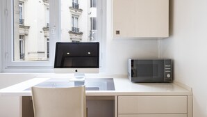 A modern, minimalist room with a desk, a computer monitor, a microwave, and a chair. - Tiny House St Germain /AC (Paris)