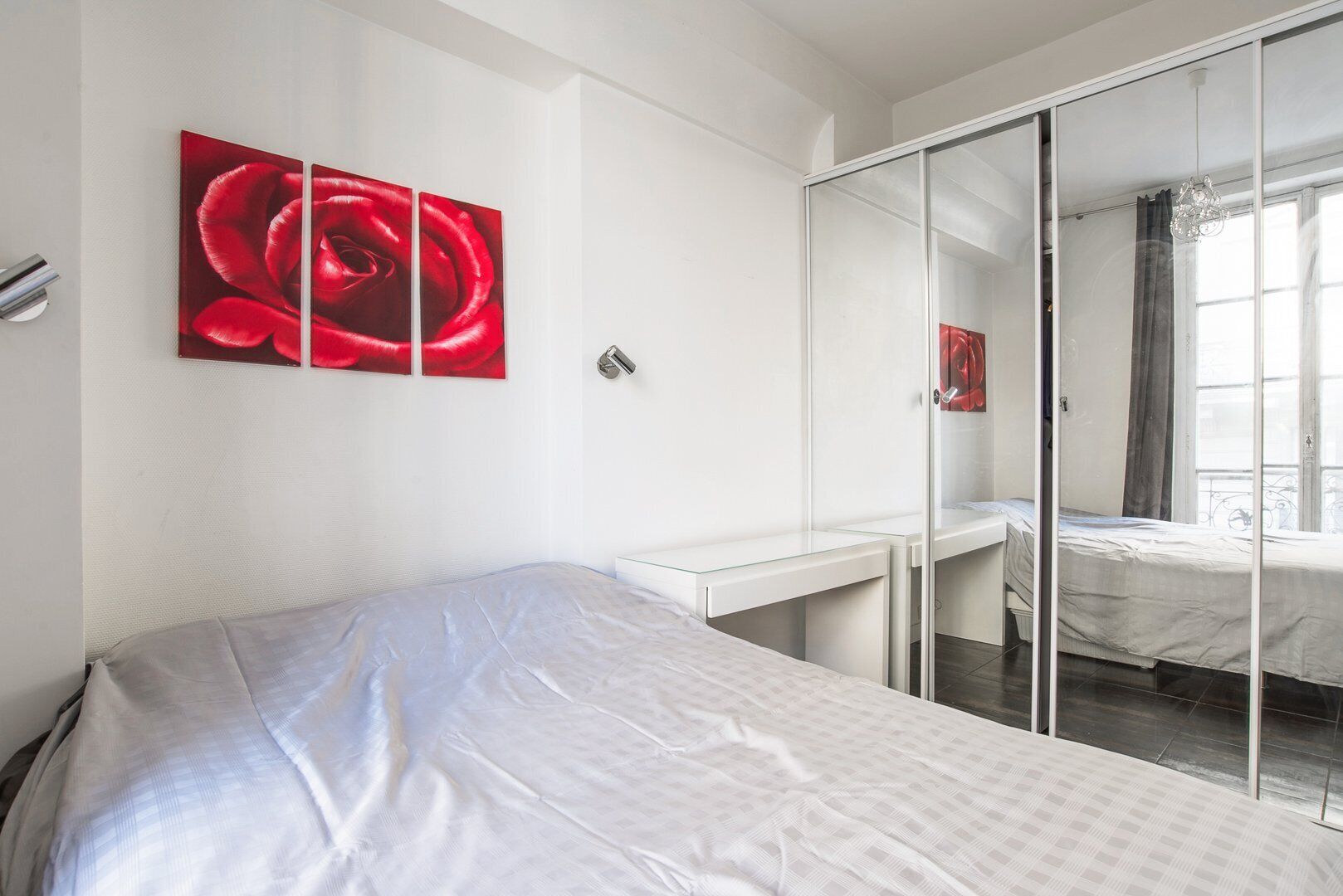 A bedroom with a bed, a desk, and a large mirror.