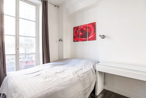 A bedroom with a bed, a window with curtains, a white wall, and a red artwork. - Paris St Germain Luxembourg (Paris)