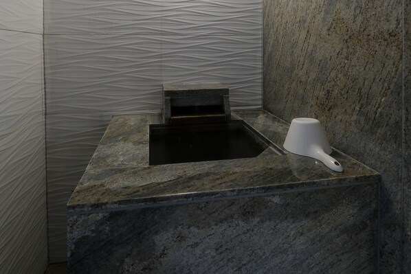 Un baño con encimera de granito, un lavabo y un dispensador de jabón blanco.