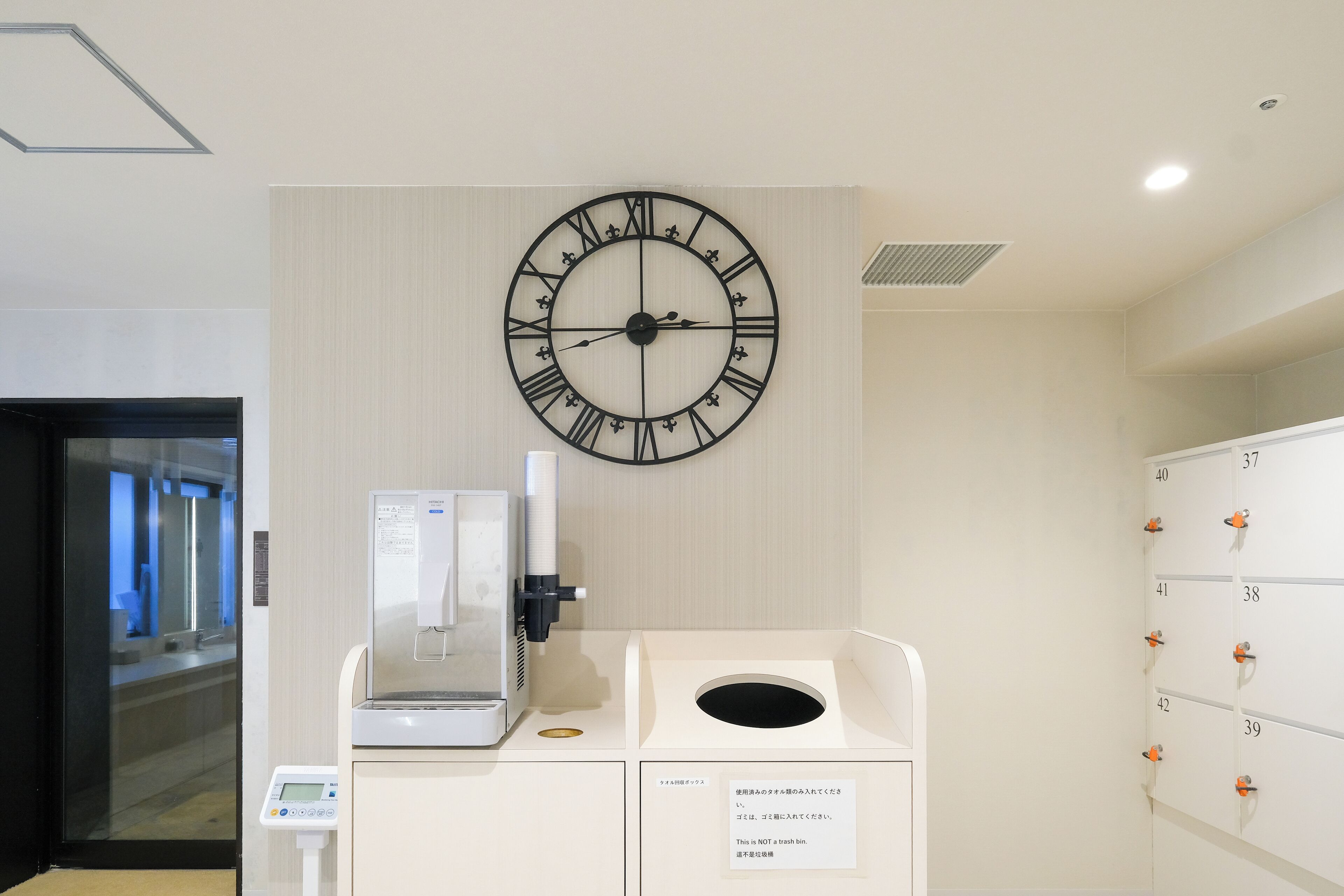 A clock, a coffee machine, and a storage unit with numbered lockers.