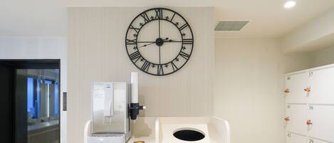 A clock, a coffee machine, and a storage unit with numbered lockers.