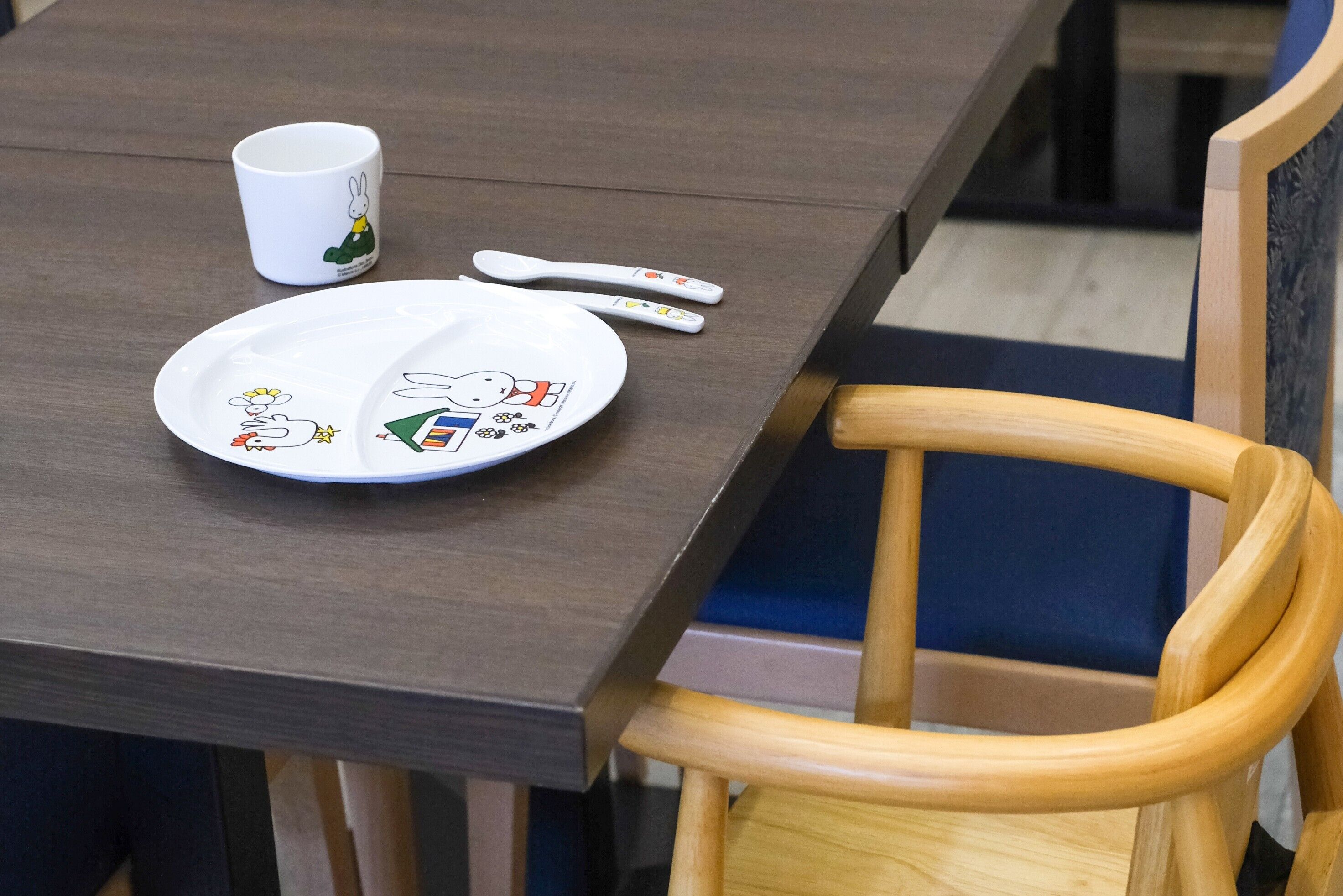 Una mesa de comedor con un plato, una cuchara y una taza.