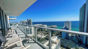 Un balcone con vista sull'oceano e sullo skyline urbano, caratterizzato da grattacieli e cielo sereno.