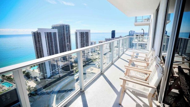 A balcony with a view of the ocean and high-rise buildings. - 2-Bedroom Luxury Condo with Balcony (Hollywood)