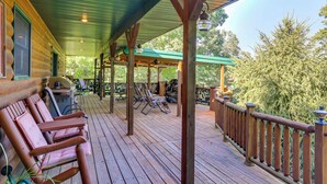 Una terraza de madera con sillones, una parrilla y un espacio cubierto con mesas y sillas.