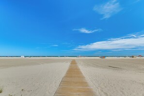 A wide sandy beach with a wooden boardwalk leading to the water. - Beachfront Wildwood Crest Condo w/ Pool Access! (Wildwood Crest)