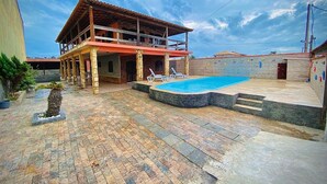 Un bâtiment à deux étages doté d’une piscine, d’un revêtement de sol en pierre et d’un balcon.