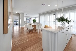 A modern kitchen with a central island, white cabinetry, and a dining area with a round table and chairs. - Hillgrove. Family Entertainer. Mountain Views. (Kelso)