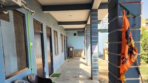 A corridor with a row of rooms, a ceiling fan, and a hanging orange cloth. - Raghubir Nikunj Homestay (Faizabad)