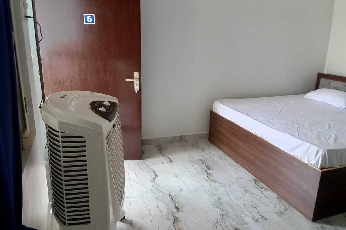 A room with a bed, a wooden door, and a white air conditioning unit.
