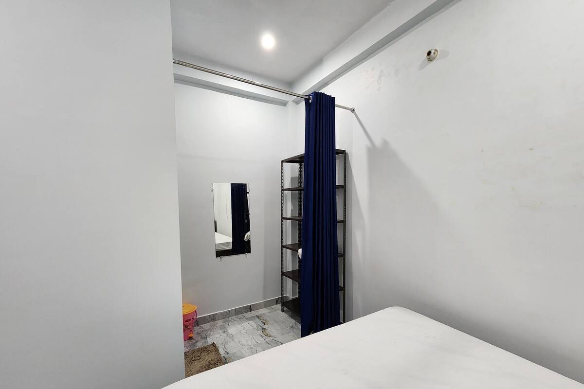 A bathroom with a white sink, a mirror, a towel rack, and a blue curtain.