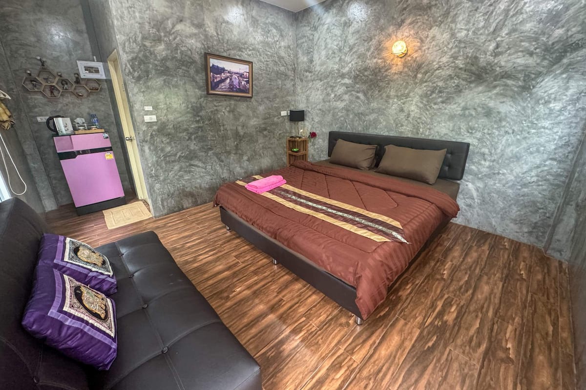 Un dormitorio con cama, sofá, una mesita y un calentador de pared.