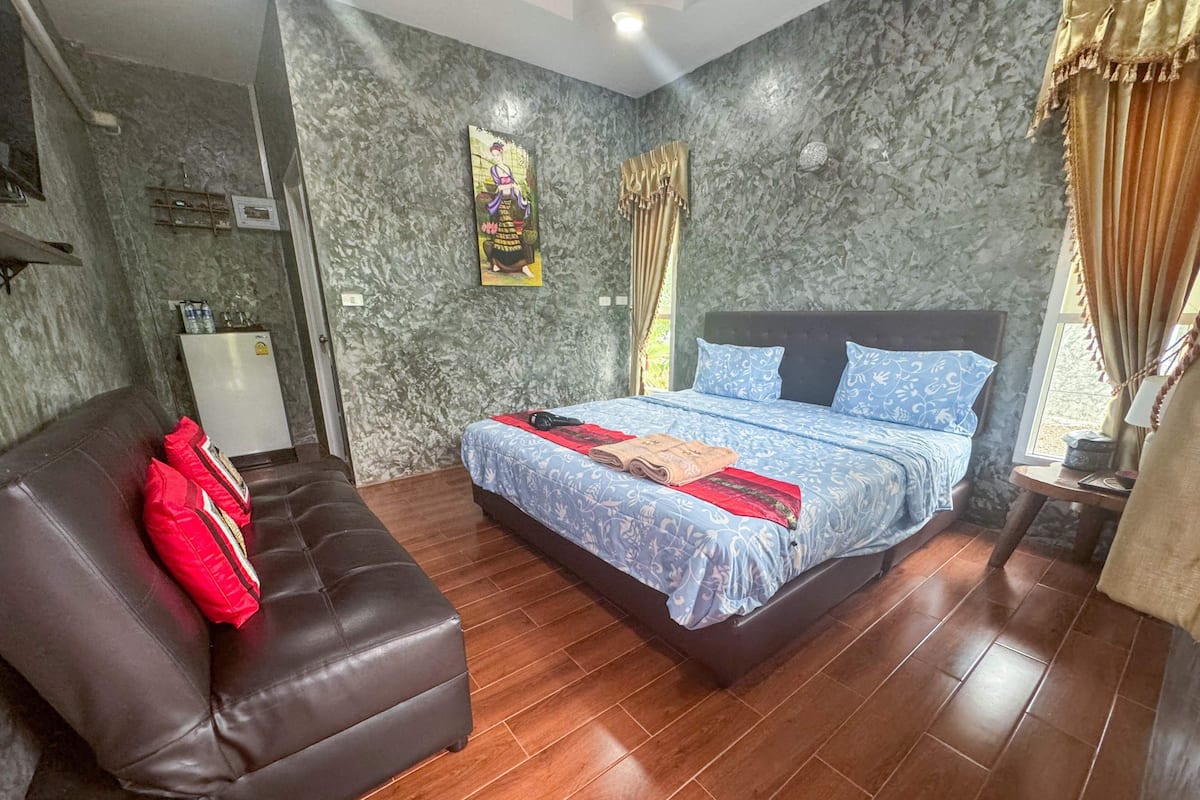 Un dormitorio con cama, sofá, una mesita y estante en la pared.