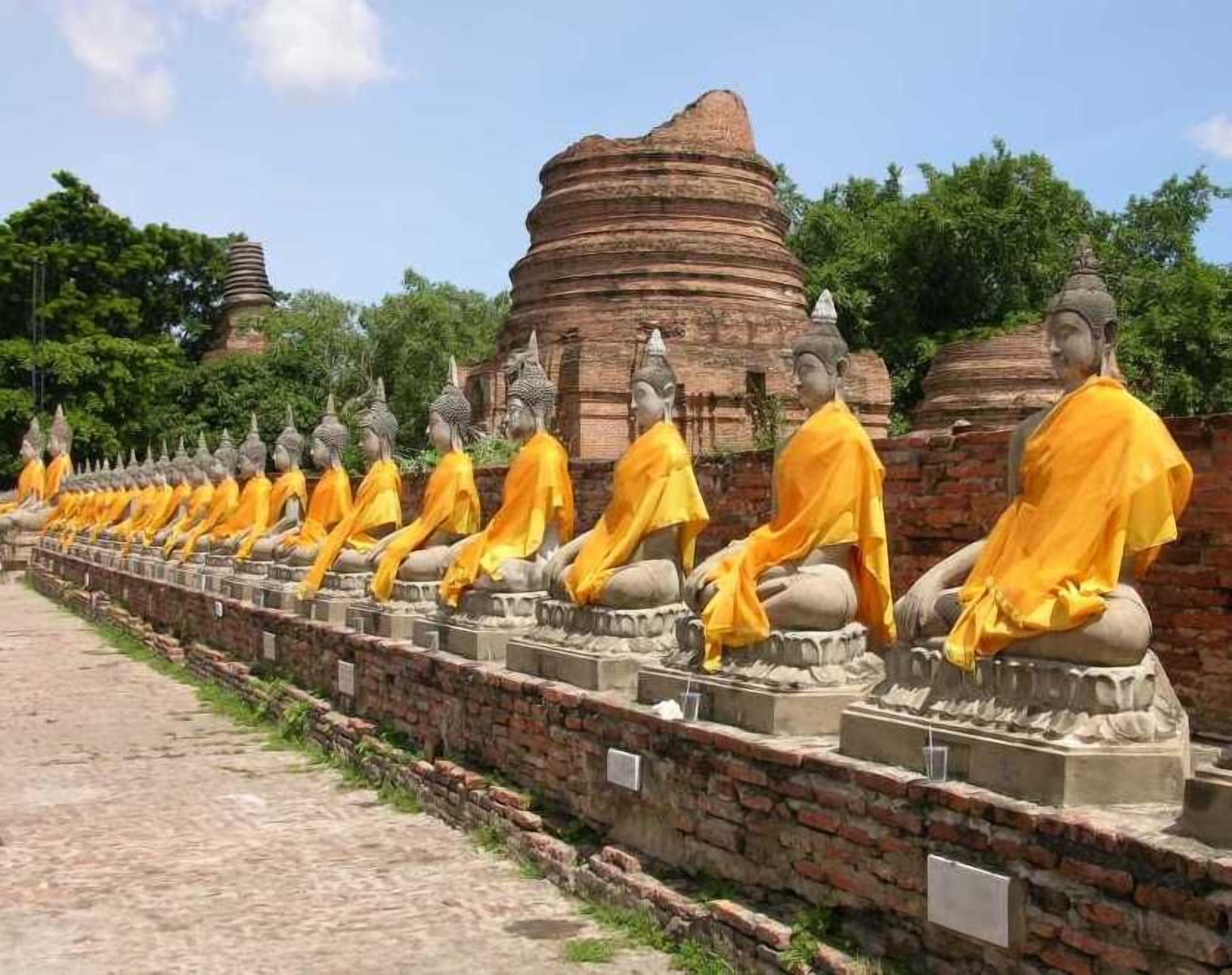 Fileira de estátuas de Buda sentadas num pátio de templo.