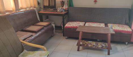 Ein Wohnzimmer mit einer Couch, einem kleinen Holztisch, einem Computertisch und einem Wandbild.
