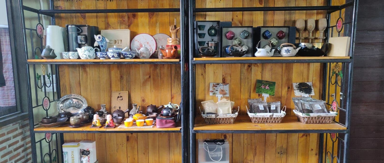 A wooden shelving unit displaying various ceramic items, including teapots, cups, and decorative pieces.