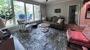 A spacious living room with a large window, a ceiling fan, and a red patterned armchair. - Cozy Waterfront Retreat at McMichael Farms (Chesterfield)