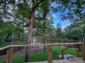 Una terraza de madera con barandilla que da a un lago, rodeada de árboles.