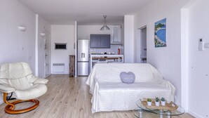 Un dormitorio moderno y minimalista con una cama blanca, una mesa de centro de vidrio y una silla blanca.