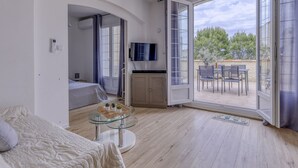 Un dormitorio moderno con una cama, una mesita de centro de vidrio y un televisor.
