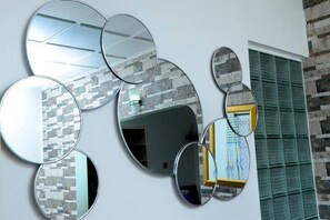 A wall with multiple round mirrors and a window with a green grid pattern. - Melloz Cozy Homes (Kampala)