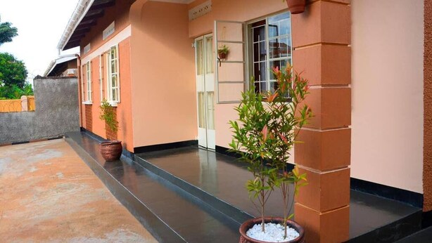 Un edificio con fachada color melocotón, entrada de baldosas y plantas en macetas.