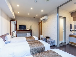 A hotel room with two beds, a desk with a TV, a small table, and a bathroom with a mirror. - Tabist City Hotel Patio (Takamatsu)
