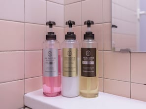 Trois bouteilles de produits de soins corporels de la marque Aromad'or sont posées sur une étagère.