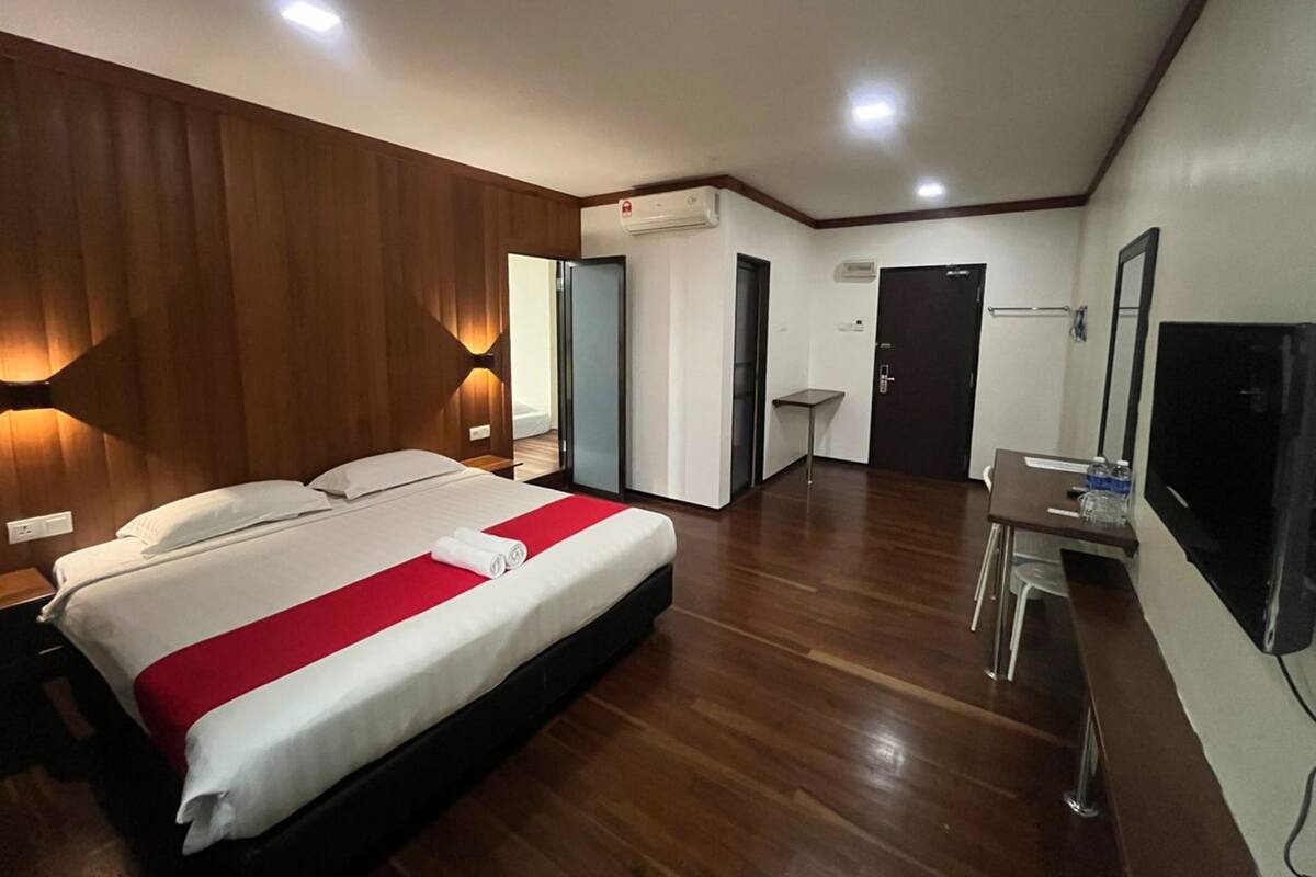 A hotel room with a bed, a desk, a TV, and a mirror.