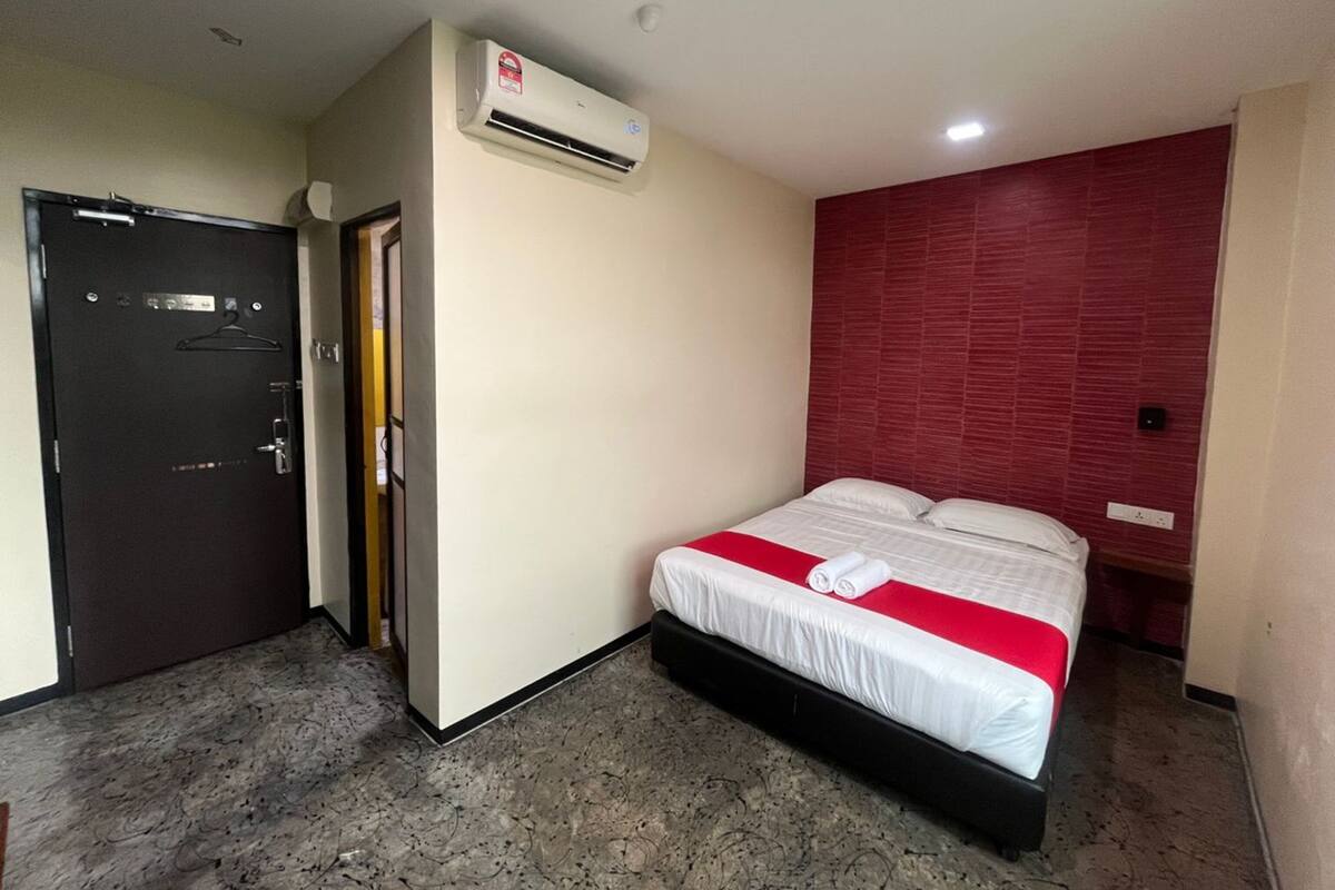 A hotel room with a bed, a wardrobe, and an air conditioning unit.
