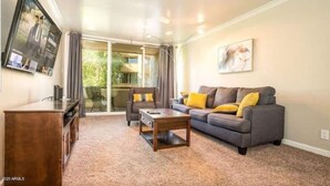 A living room with a sofa, coffee table, and a TV mounted on the wall.