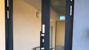 En hotelindgang med en mørkeblå dør, et metaltrin og en synlig elevator i baggrunden.