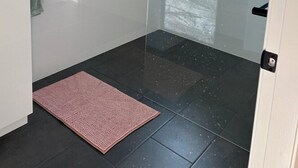 A modern bathroom with a glass shower enclosure, a small window, and a white sink.