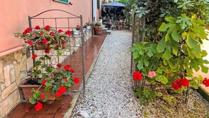 Un sendero en un jardín que conduce a un edificio con un muro de piedra y una verja de metal.